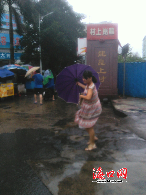 市民在風(fēng)雨中艱難地撐著雨傘行走