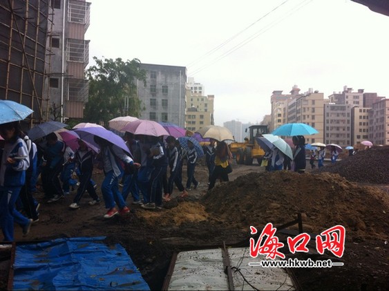 學(xué)生走在正在施工的道路上 旁邊一輛推土機正在作業(yè)