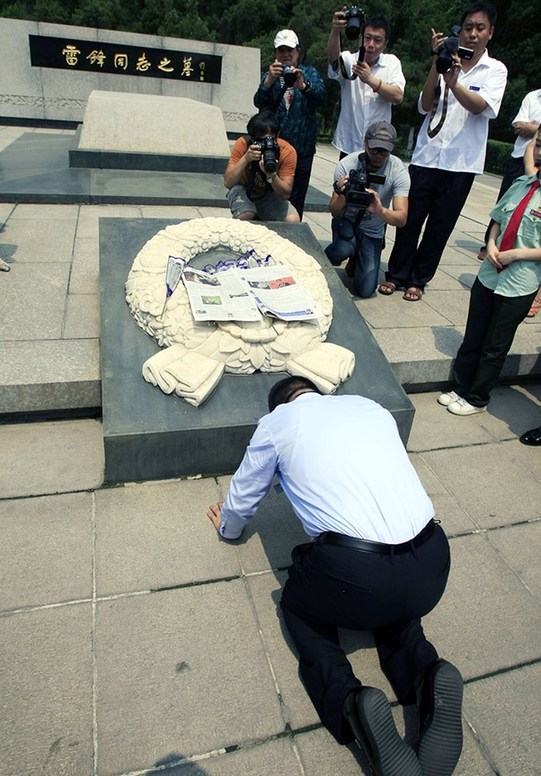 2014年7月1日，辽宁抚顺，陈光标在雷锋墓前磕头祭献报纸，并汇报美国感恩之旅。
