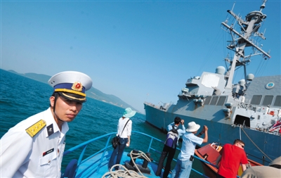 2012年4月，一场美越联合救援演习结束后，参加演习的越南民众拍摄美军军舰，一名越南海军官员站在一旁。资料图片