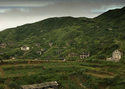 无人村,自海遥望,废弃的房屋爬满了绿色植物,人去楼空,门径荒芜.