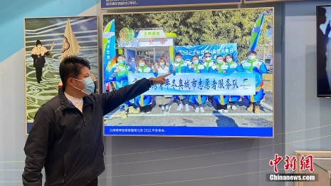 图为北京大学体育教研部台湾教师陈文成在展览的台湾青年志愿者照片前。 <a target='_blank' href='/'>中新社</a>记者 朱贺 摄