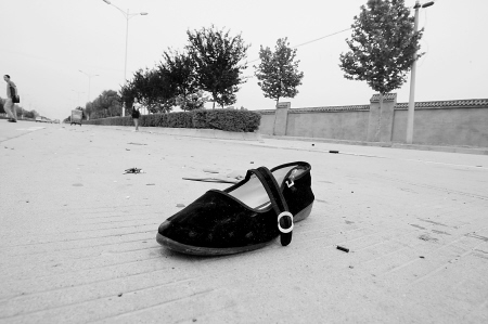事故现场,黑色的女式布鞋孤零零地留在马路中间.