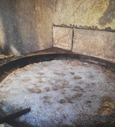 占地约六七十平米的前后两院,前院摆满了油迹斑斑的油桶,后院两口大锅
